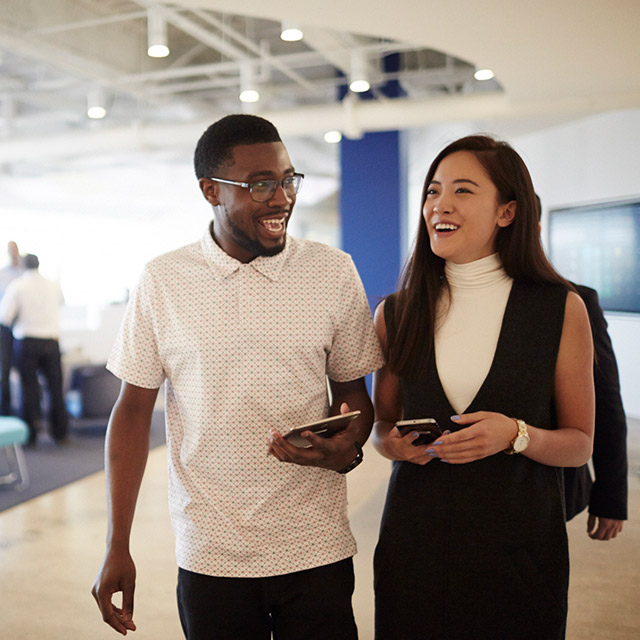 Two people standing side by side holding mobile devices.